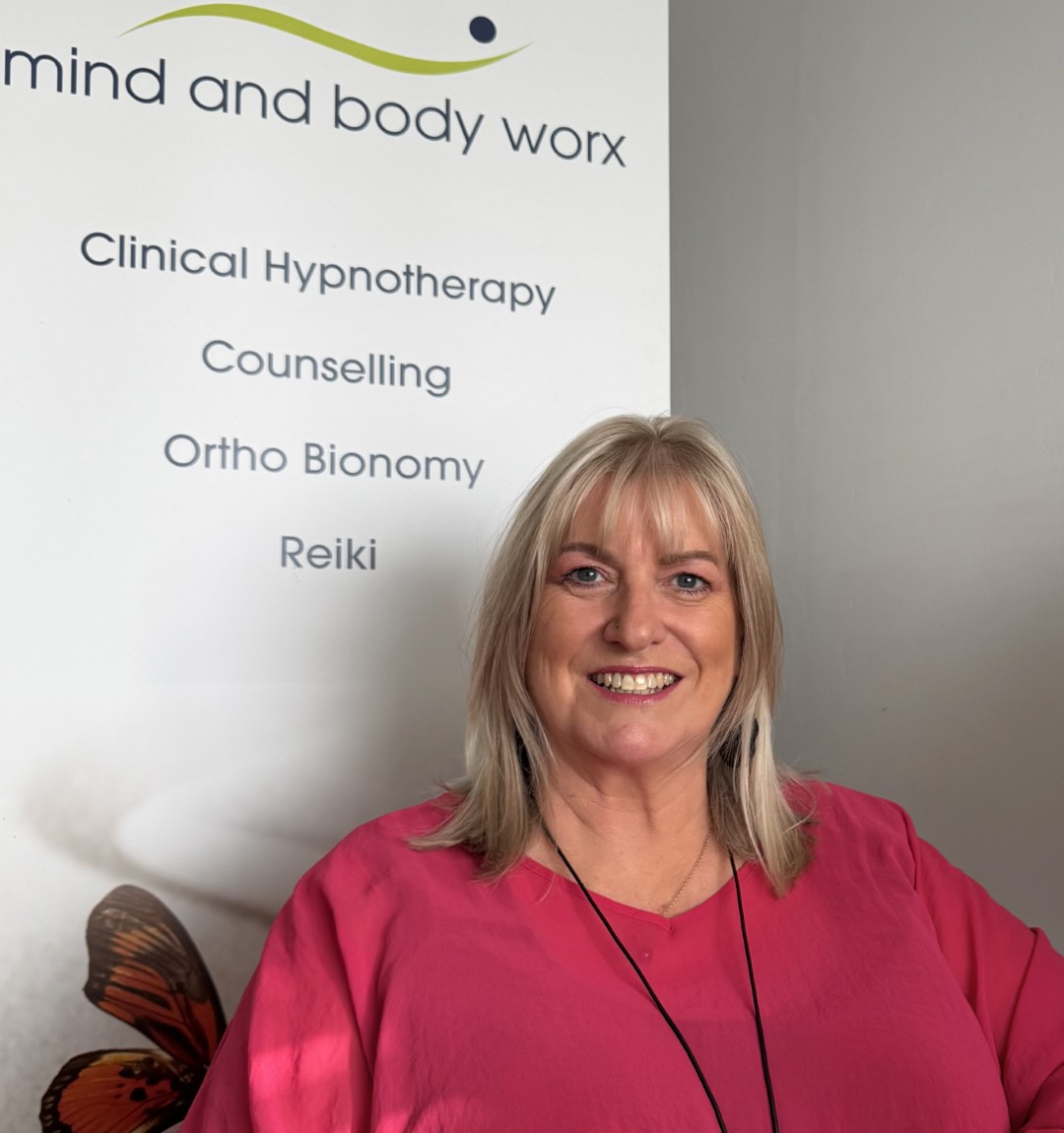Sheryl Murray in front of the Mind and Body Worx clinic banner